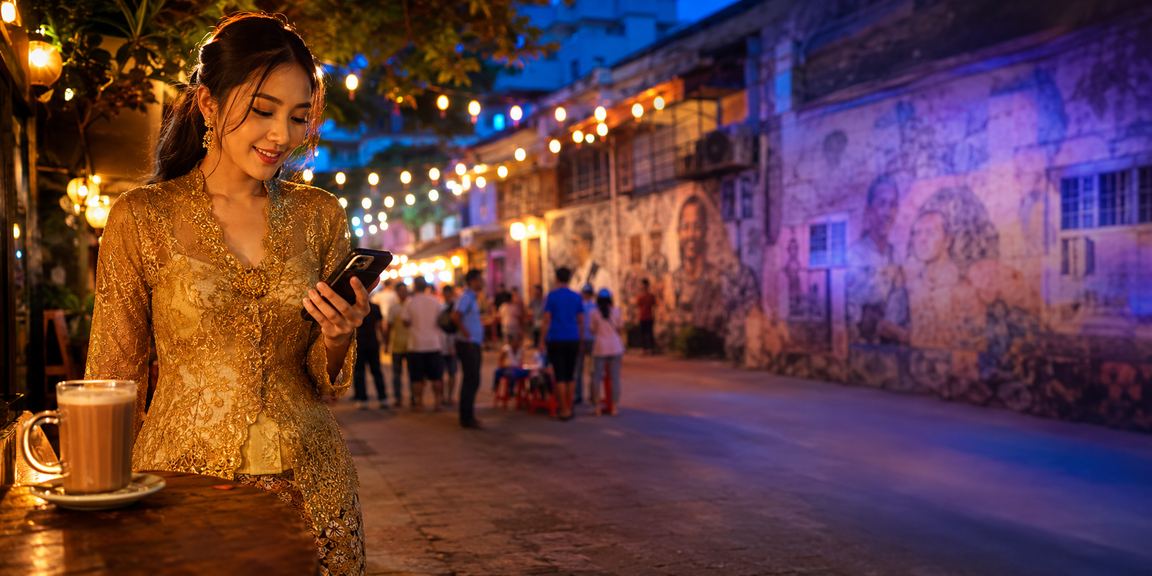 Pengguna Pulau Pinang mengakses platform p0500 melalui telefon dengan pakaian kebaya